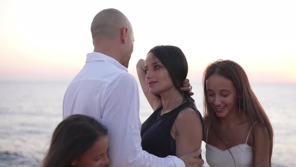 Happy Father and Mother Hugging As Joyful Daughters Dancing Around in Slow Motion at Picturesque