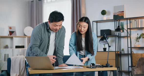 30-s Chinese Startuppers Working Together Over Joint Presentation, Browsing Reports with Charts 