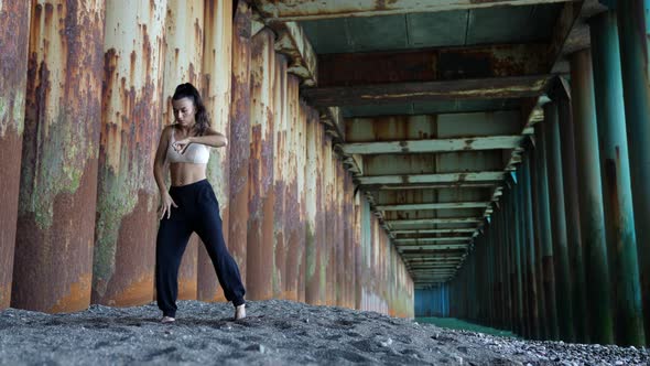 a Barefoot Woman Dances Under the Pillars of the Bridge