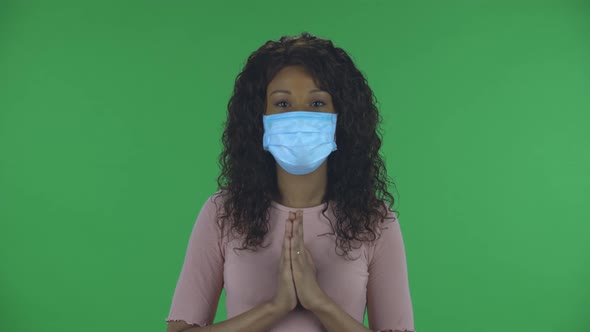 Portrait of Beautiful African American Young Woman in Medical Mask Is Looking Straight and Prays