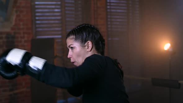 Female Boxer Training in the Dark Ring