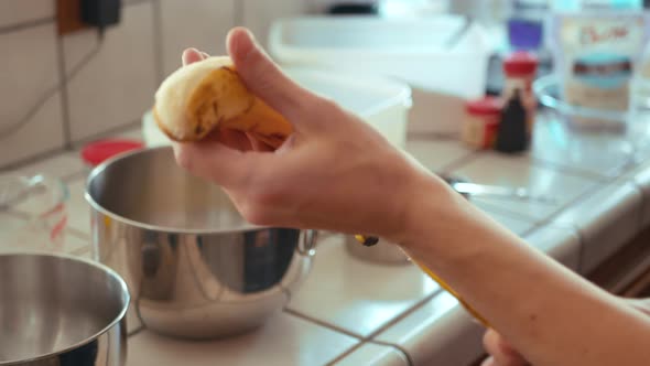 Chef peeling a ripe banana while baking banana bread in kitchen.