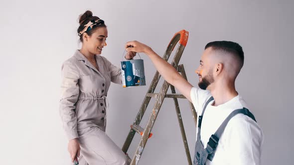 Wife Standing on a Ladder While Her Husband Paints the Wall
