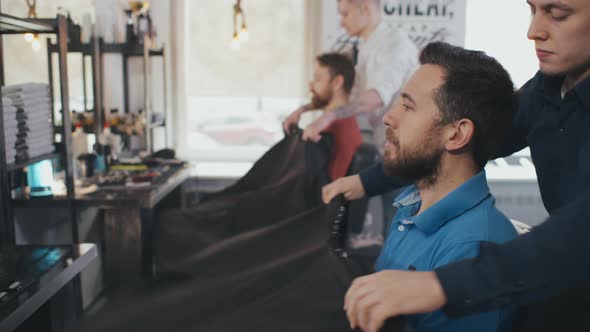 Young Handsome Barber Put a Sheet To Cover His Client From Cut Hair