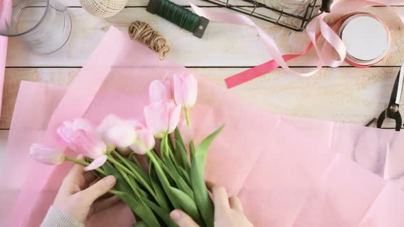 Time-lapse. Step by step. Florist wrapping pink tulips in bouquet