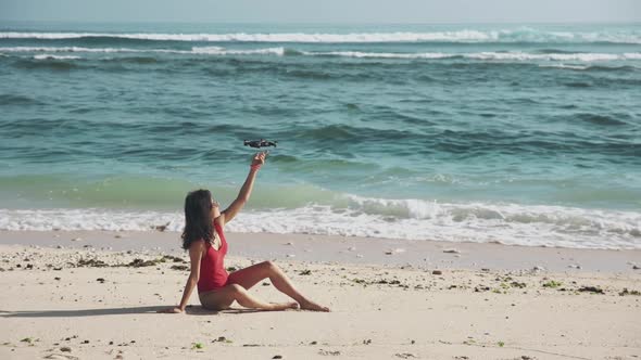 Portrait of Beautiful Brunette Sitting on the Sand By the Ocean