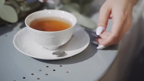 White Cup with Tea Stands on Table in Fresh Air