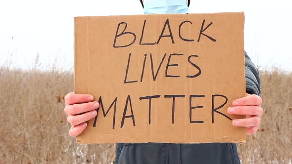 A Caucasian Man Holds a Sign with the Words BLACK LIVES MATTER