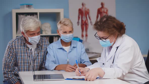 Elderly Couple in Safety Mask Visiting Young Woman Doctor