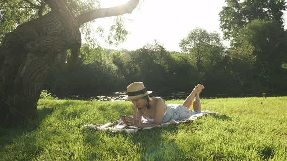 Cute lady in earphones listening to music, enjoying warm sunny day outdoor and relaxing in park