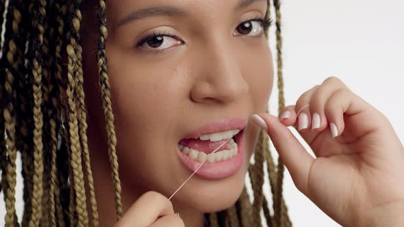 African Female Flossing Teeth With Tooth Floss Over White Background