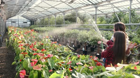 Woman with Daughter Watering Plants at Indoor Plantation