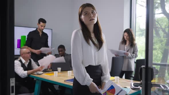 Overwhelmed Troubled Young Beautiful Caucasian Woman Sighing As Colleagues Throwing Paperwork at