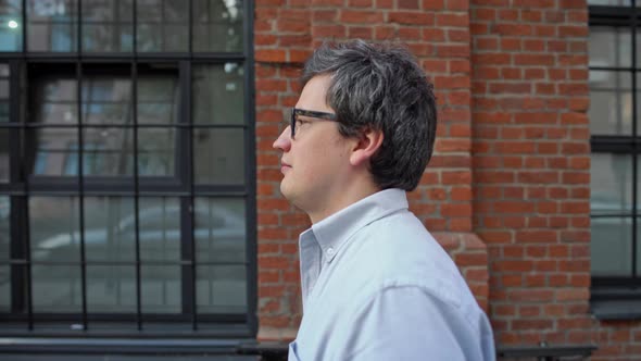 Portrait Profile Shot of Man in Eyeglasses and Blue Shirt Walking Along the Street