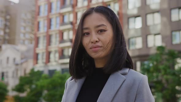 Young Adult Asian Woman Turning Her Head and Looking Into the Camera in the City