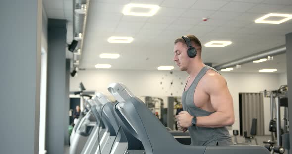 Athlete in Headphones on a Treadmill at Gym