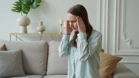 Unhappy Woman Suffering From Head Ache at Home Sitting on the Couch