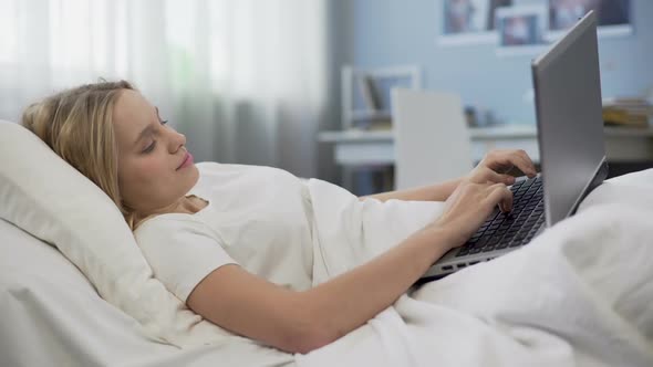 Smiling Teenager Communicating in Social Networks, Lying in Bed, Morning Time