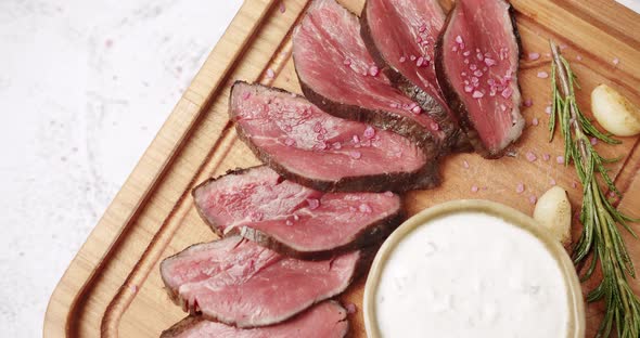 Grilled Rare Medium Beef Meat with Garlic and Rosemary in a Woden Plate