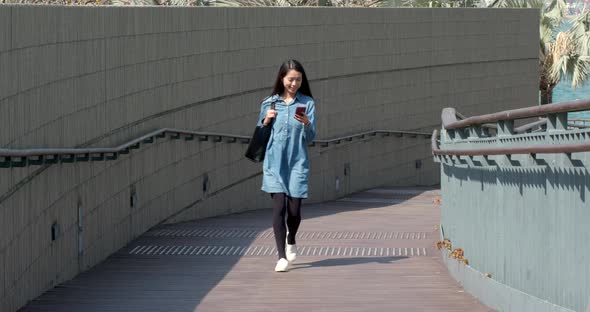 Woman walking in the city street and use of mobile phone