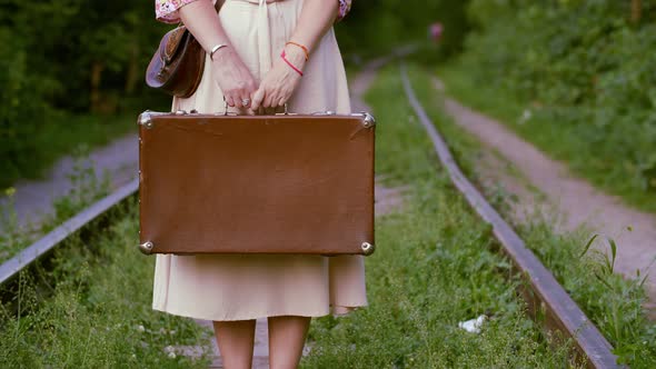 Female Hands Holding Vintage Suitcase on Railway Background at Summer. Tourist Woman with Retro