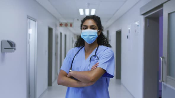 Portrait of asian female doctor wearing face mask and scrubs standing in hospital corridor