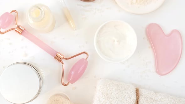 Rotation of Pink Quartz Facial Roller and Glass Bottle with Pipette with Gel Fluid Collagen Serum