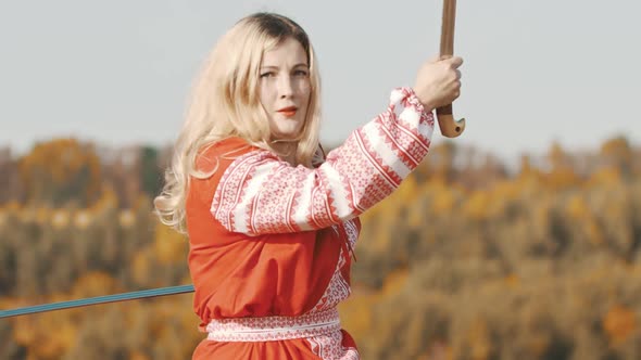 Feisty Blonde Woman in Red National Dress Fighting with Two Swords