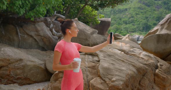 Woman Makes a Video Selfie for Vlog After Exercise Holds White Thermo Cup and Talking to the Camera