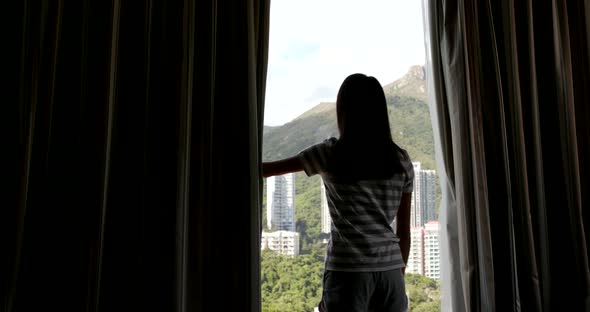 Woman open the window curtain  