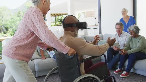 Happy senior diverse people with man in wheelchair using vr headset at retirement home