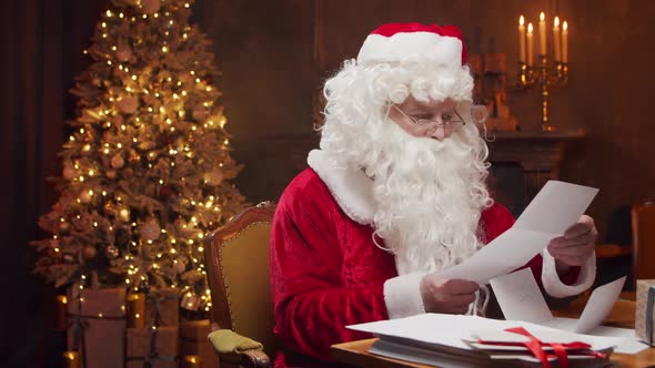 Workplace of Santa Claus. Cheerful Santa is working while sitting at the table.