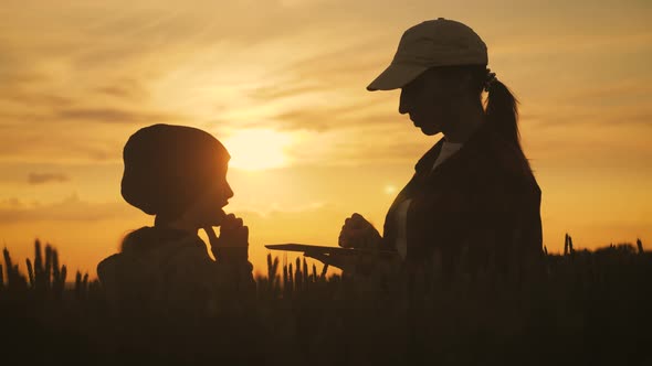 Young Mother Farmer Teaches Her Daughter To Work in a Wheat Field