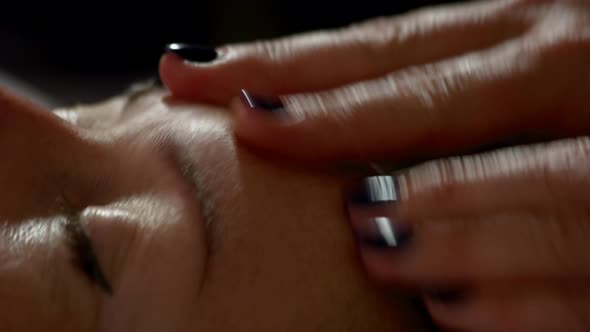 Close Up of Massage Therapist Hands Massaging Female Forehead