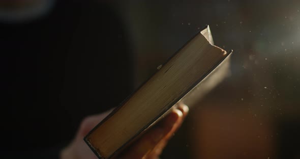 Close-up, Hands Are Closes a Very Old Book and Dust Fron It Is Fliying. Ray of Light. A Beautiful