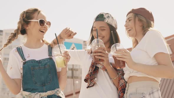 Positive models holding and drinking fresh cocktail smoothie outdoors