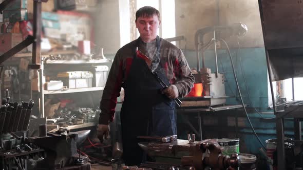 Man Blacksmith Forming a Leaf Out of Hot Piece of Metal and Looking at It with a Smile