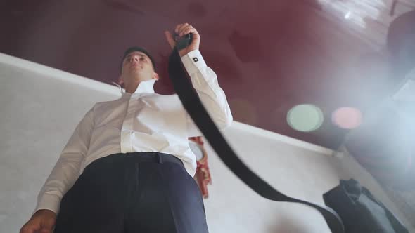 Groom wears belt in slow motion. Man in white shirt puts belt. Slow motion