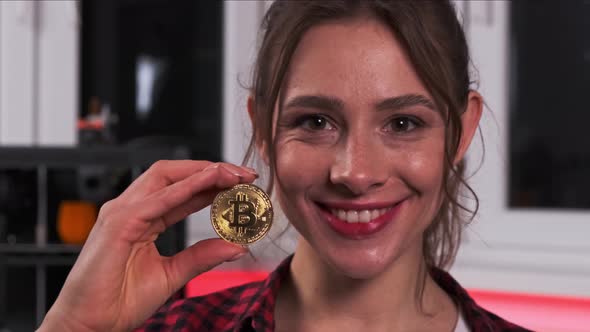 Portrait of an Attractive Tech Woman with Charming Smile Holding Golden Bitcoin in Her Hand