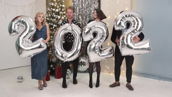 Group of Friends Holding Inflatable Foil Numerals 2022