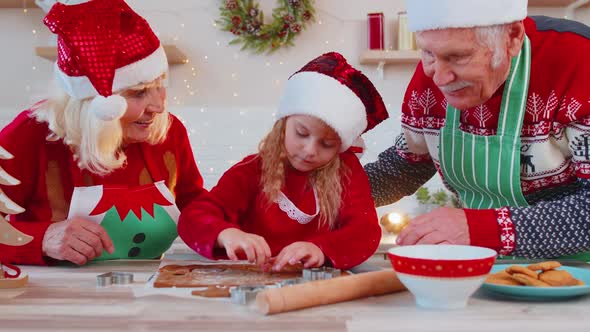 Senior Family Grandparents with Granddaughter in Santa Claus Hats Preparing Cooking Homemade Cookie