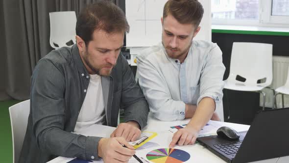 Male Business Colleagues Doing Paperwork Together at the Office