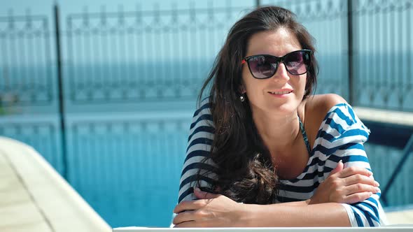 Portrait Happy Smiling Woman in Sunglasses Enjoying Vacation Lying on Deck Chair with Arms Crossed