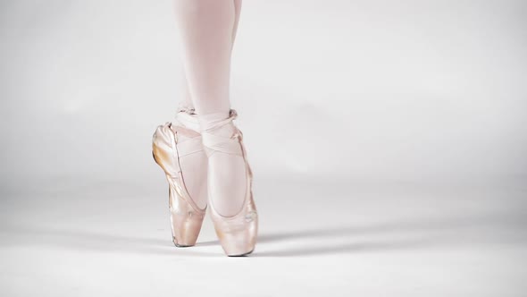 Beautiful Legs of a Ballerina in Pointe on a White Background Closeup