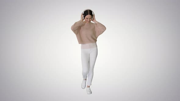Smiling Female with Headphones Walking and Dancing To the Music on Gradient Background