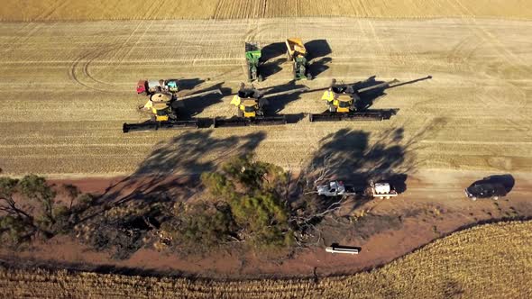 Combines, tractors and trailers ready to go to the fields to harvest corn - aerial view