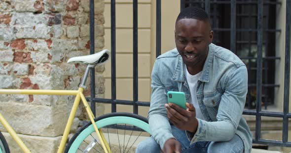 Cheerful African American Young Man Having a Video Call Via His Smartphone. Guy Waving and Smiling