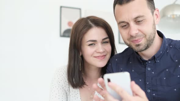 Happy and Loving Husband and Wife are Viewing Photos or Videos on Their Phone