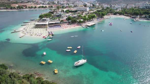 Aerial Azure Beach with Empty Sun Loungers and Boats Balkan Sea Coast Albania