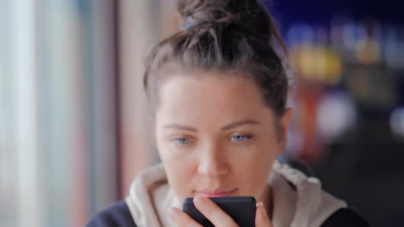 Beautiful Blue Eyed Woman Text Messaging with Her Mobile at Cafe